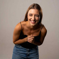 Thumbnail for Smiling woman with brown hair wearing a black top and jeans, conveying joy and happiness.
