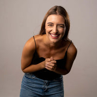 Thumbnail for Smiling woman in a black top and jeans, exuding warmth and happiness, showcasing a light-hearted moment.