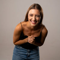 Thumbnail for Smiling woman wearing a black top and denim skirt, showcasing happiness and joy.