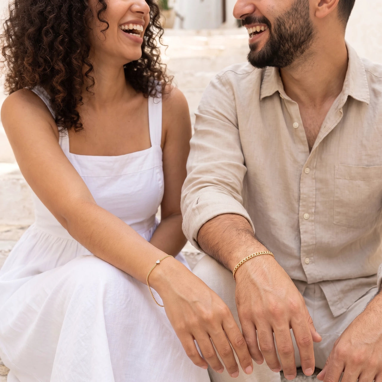 Heart Bond Matching Bracelet Set in Gold — worn by a couple sitting on sunlit stone steps