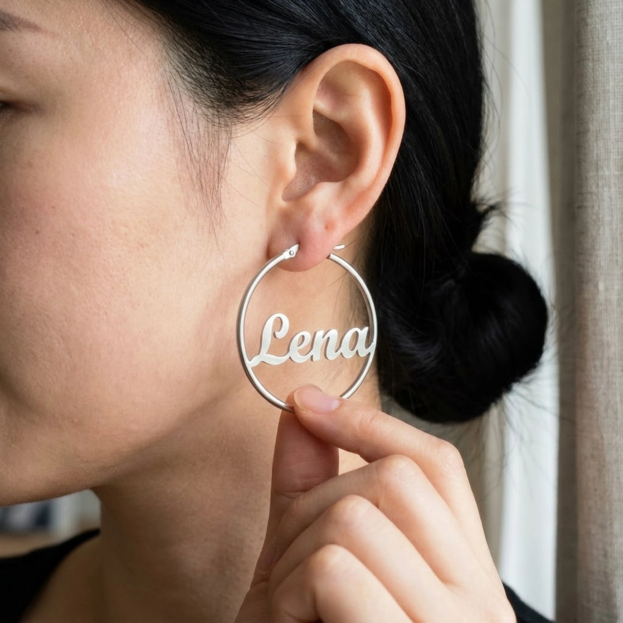 Custom Name Hoop Earrings in Silver held between the fingertips, scale reference | SKU: name-hoop-silver-30-mm