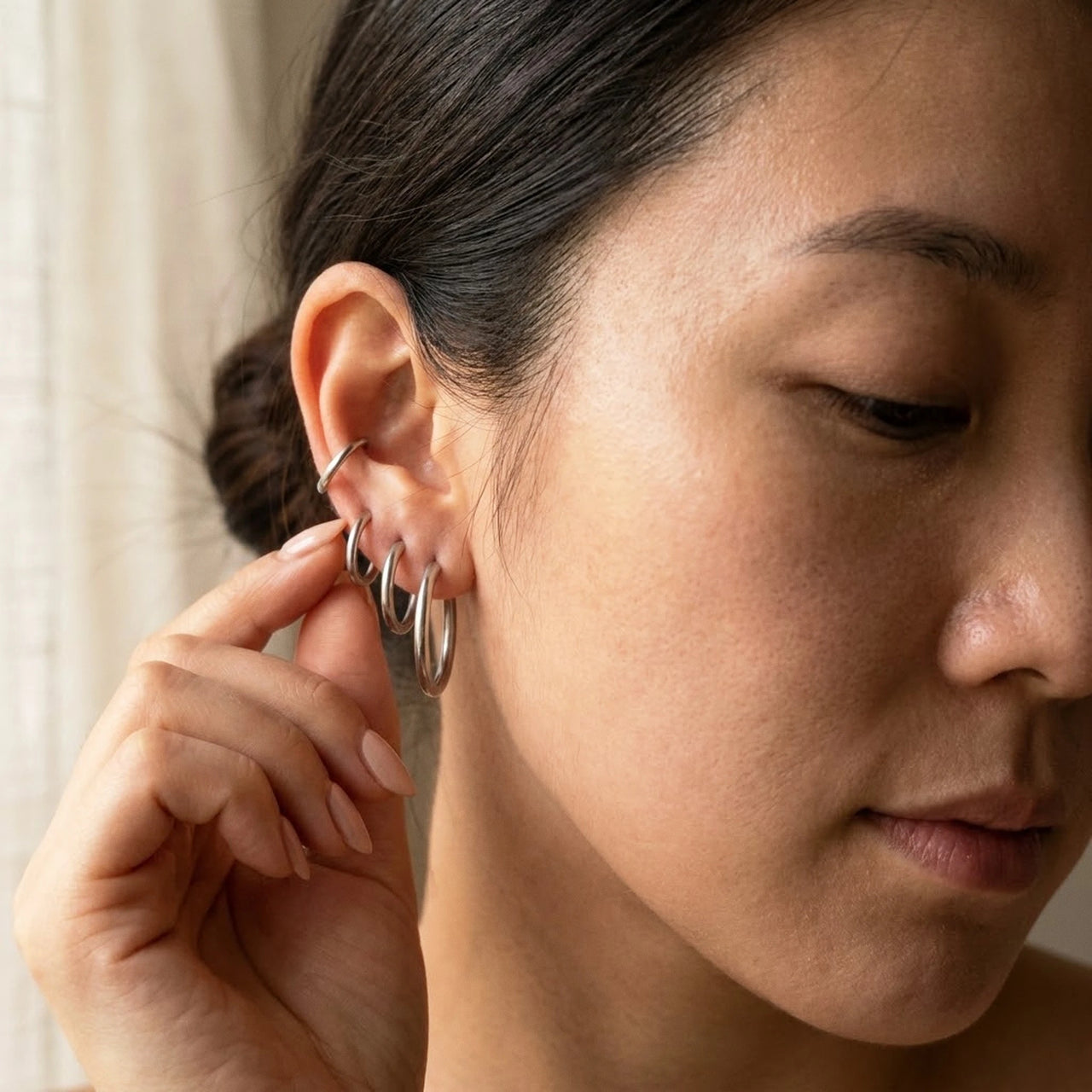 Huggie Hoop Earrings Set of 4 Pairs in Silver held between the fingertips, scale reference | SKU: huggie-set-silver